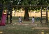 Two children playing on swings in a sunny park, capturing summer fun and friendship.