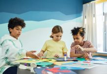 Children focusing on an art project with colored papers in a playful art class setting.