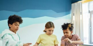 Children focusing on an art project with colored papers in a playful art class setting.
