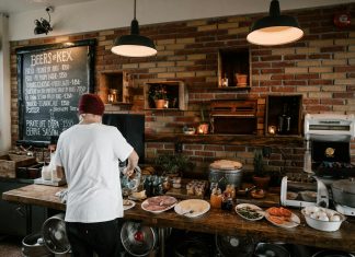 Best Breakfast in Hoboken: Your Ultimate 2026 Guide to Morning Eats Person serving food in a cozy cafe with rustic brick walls and wooden buffet table.