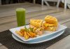 Savor a waffle sandwich with fries and a refreshing green juice, perfect for dining outdoors.
