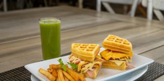 Savor a waffle sandwich with fries and a refreshing green juice, perfect for dining outdoors.