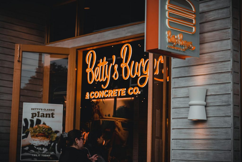 Entrance of Betty's Burgers restaurant with illuminated signage and open door at night.