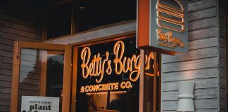 Entrance of Betty's Burgers restaurant with illuminated signage and open door at night.