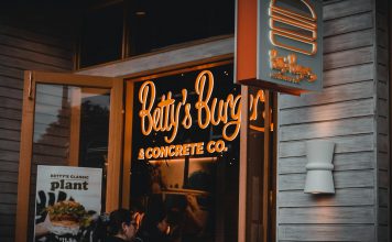 Entrance of Betty's Burgers restaurant with illuminated signage and open door at night.
