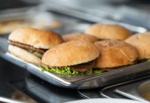 Appetizing close-up of freshly made burgers on a stainless steel tray, ready to serve.