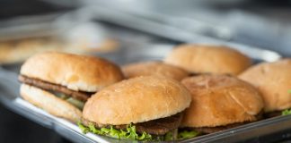 Appetizing close-up of freshly made burgers on a stainless steel tray, ready to serve.