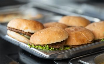Appetizing close-up of freshly made burgers on a stainless steel tray, ready to serve.