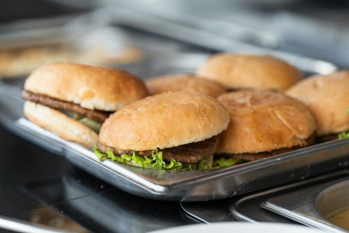 Appetizing close-up of freshly made burgers on a stainless steel tray, ready to serve.
