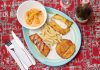 Delicious Colombian seafood platter featuring shrimp, fried plantains, and fish with a creamy sauce.
