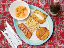 Delicious Colombian seafood platter featuring shrimp, fried plantains, and fish with a creamy sauce.