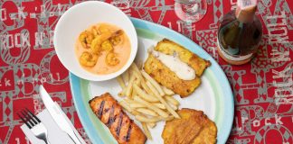 Delicious Colombian seafood platter featuring shrimp, fried plantains, and fish with a creamy sauce.