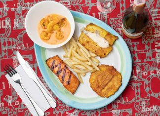 Delicious Colombian seafood platter featuring shrimp, fried plantains, and fish with a creamy sauce.