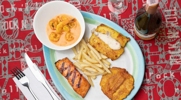 Delicious Colombian seafood platter featuring shrimp, fried plantains, and fish with a creamy sauce.