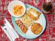 Delicious Colombian seafood platter featuring shrimp, fried plantains, and fish with a creamy sauce.