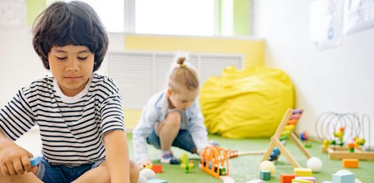 Kids enjoying playtime with toys and blocks in a bright kindergarten classroom.