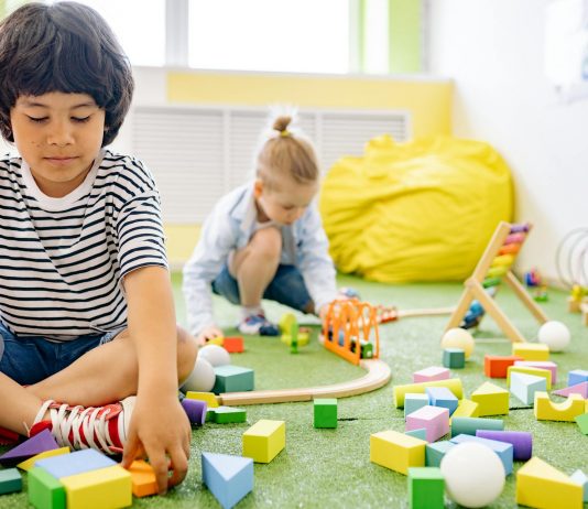 Kids enjoying playtime with toys and blocks in a bright kindergarten classroom.