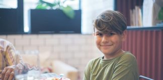 Cute child smiling at a family dining table, enjoying a meal indoors.
