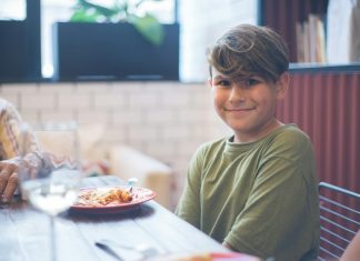Best Family Restaurants in Newark NJ for a Stress-Free Meal in 2026 Cute child smiling at a family dining table, enjoying a meal indoors.