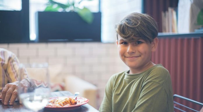 Cute child smiling at a family dining table, enjoying a meal indoors.