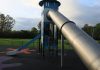 A modern outdoor playground slide set in a green park in England.
