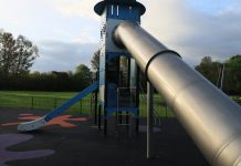 A modern outdoor playground slide set in a green park in England.