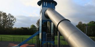 A modern outdoor playground slide set in a green park in England.