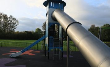 A modern outdoor playground slide set in a green park in England.