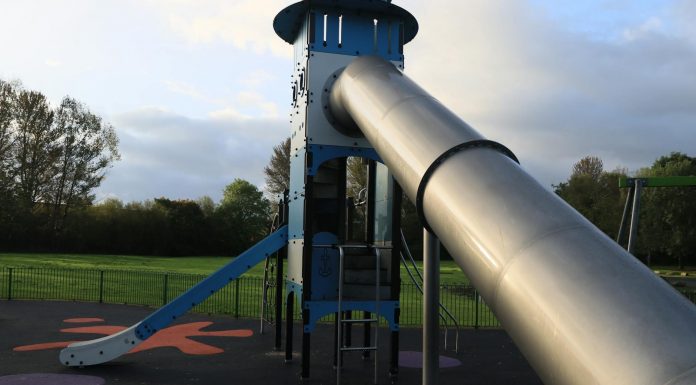 A modern outdoor playground slide set in a green park in England.
