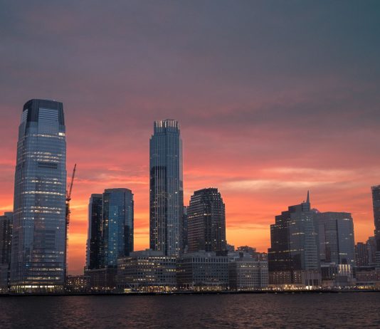 Stunning view of New York City skyline with a vibrant sunset reflecting on skyscrapers.
