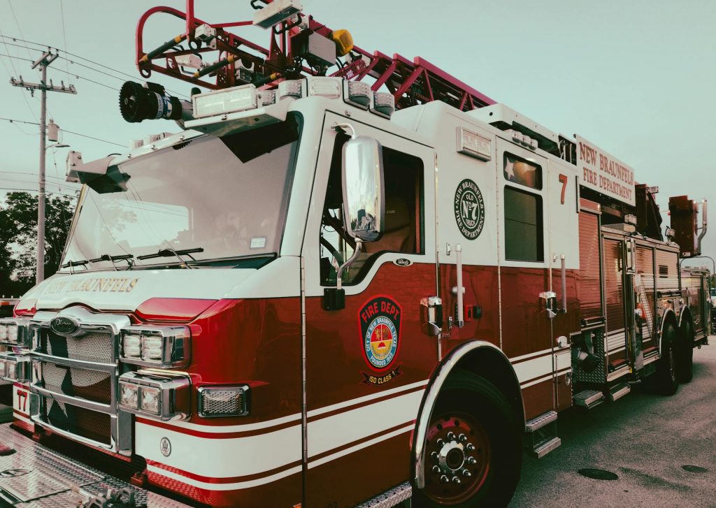 Red and white fire truck from New Braunfels Fire Department parked outdoors.