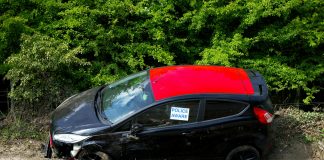 A black and red car, marked by police, abandoned off a road in Welwyn Garden City, UK.