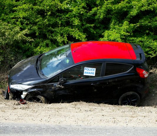 A black and red car, marked by police, abandoned off a road in Welwyn Garden City, UK.
