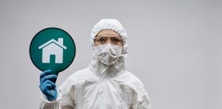 A person in protective gear with a stay safe home symbol, promoting health and safety.