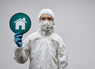BREAKING: New Virus Outbreak in 2026 Under Watch A person in protective gear with a stay safe home symbol, promoting health and safety.