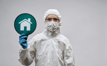 A person in protective gear with a stay safe home symbol, promoting health and safety.