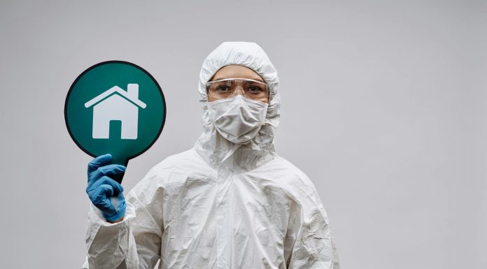A person in protective gear with a stay safe home symbol, promoting health and safety.