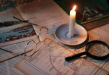 Cozy vintage scene with candle, map, glasses, and magnifying glass.