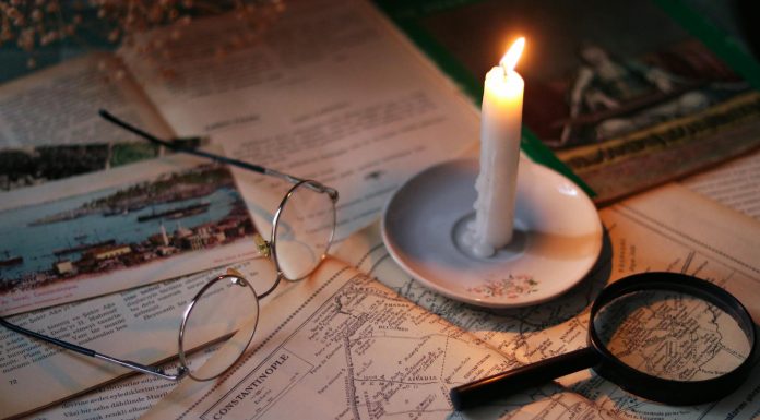 Cozy vintage scene with candle, map, glasses, and magnifying glass.