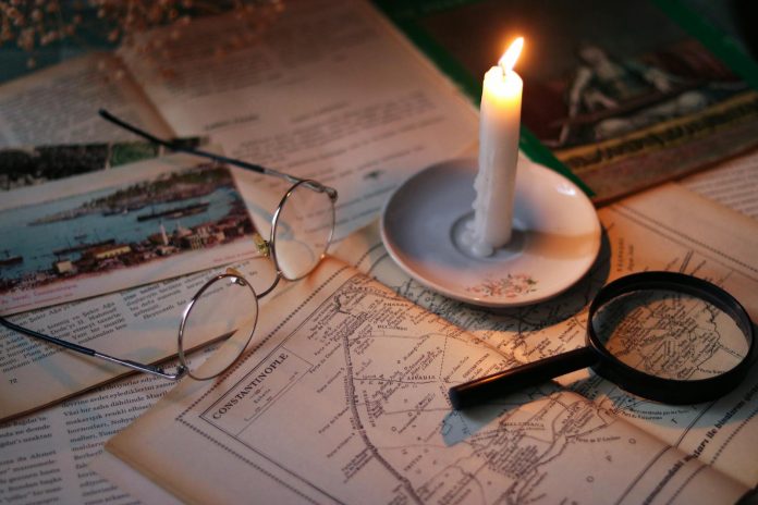 breaking-thomas-stechschulte-obituary-published-in Cozy vintage scene with candle, map, glasses, and magnifying glass.