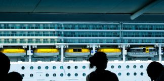 Silhouettes of people observing a large cruise ship from a dock in Türkiye.