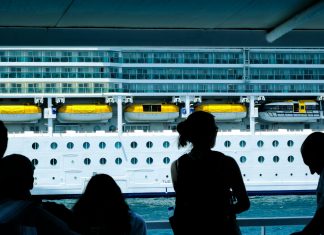 Silhouettes of people observing a large cruise ship from a dock in Türkiye.