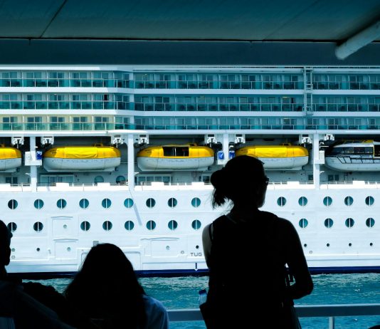 Silhouettes of people observing a large cruise ship from a dock in Türkiye.