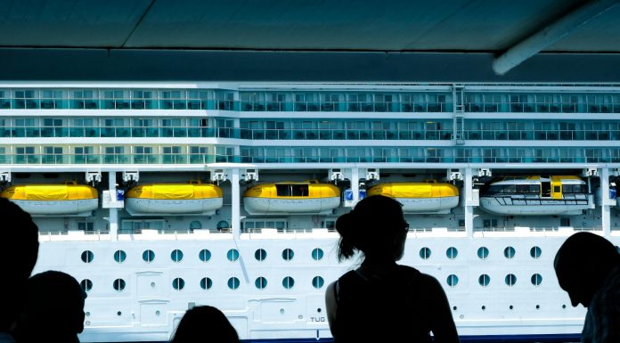 Silhouettes of people observing a large cruise ship from a dock in Türkiye.