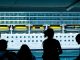 Silhouettes of people observing a large cruise ship from a dock in Türkiye.