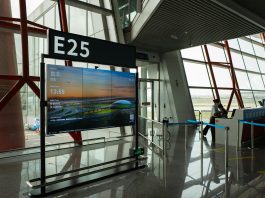 A view of a modern airport terminal showcasing Gate E25 with a flight display board.