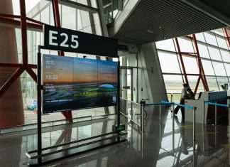 CDC seeks airport volunteers for Ebola screenings as DRC outbreak grows A view of a modern airport terminal showcasing Gate E25 with a flight display board.