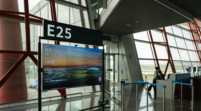 A view of a modern airport terminal showcasing Gate E25 with a flight display board.