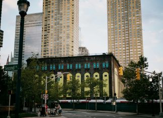 A vibrant intersection in Jersey City with towering skyscrapers and a historic building.