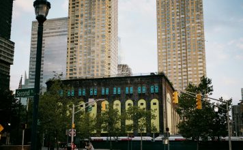 A vibrant intersection in Jersey City with towering skyscrapers and a historic building.